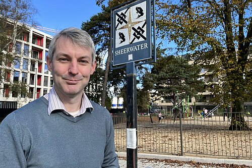 Will Forster standing in front of Sheerwater sign