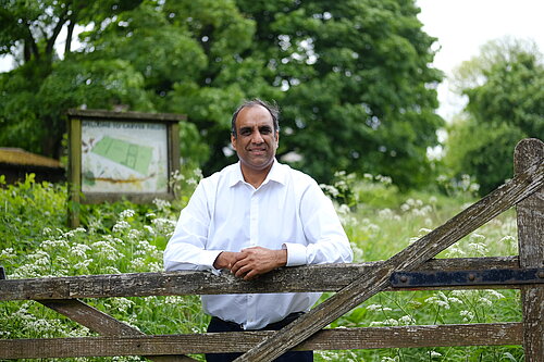 Cllr Shaffaq Mohammed in front of a field with flowers in