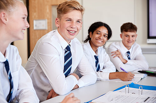 Four secondary school children sitting at a desk.