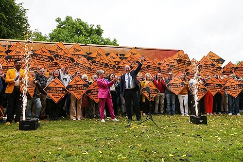 Ed Davey and Daisy Cooper in front of a crowd holding Lib Dem diamond signs