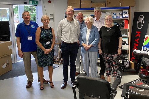 Richard Foord standing with a group of people in the showroom for TRIP Honiton. There are two to his right, and four on the left, with a motorised wheelchair in front of them