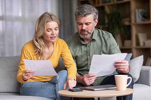 Middle aged husband and wife calculating their budget together.