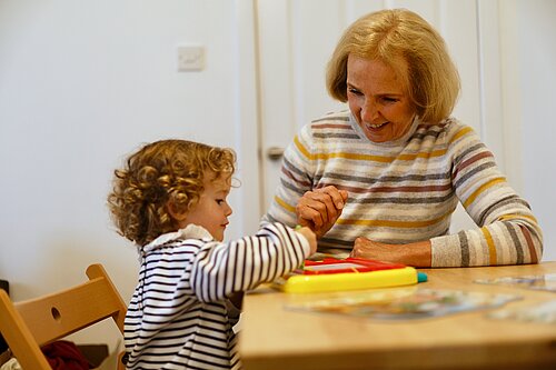 Susan Murray sitting at a table with a child playing a game.