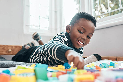 Child lying on floor playing with toys